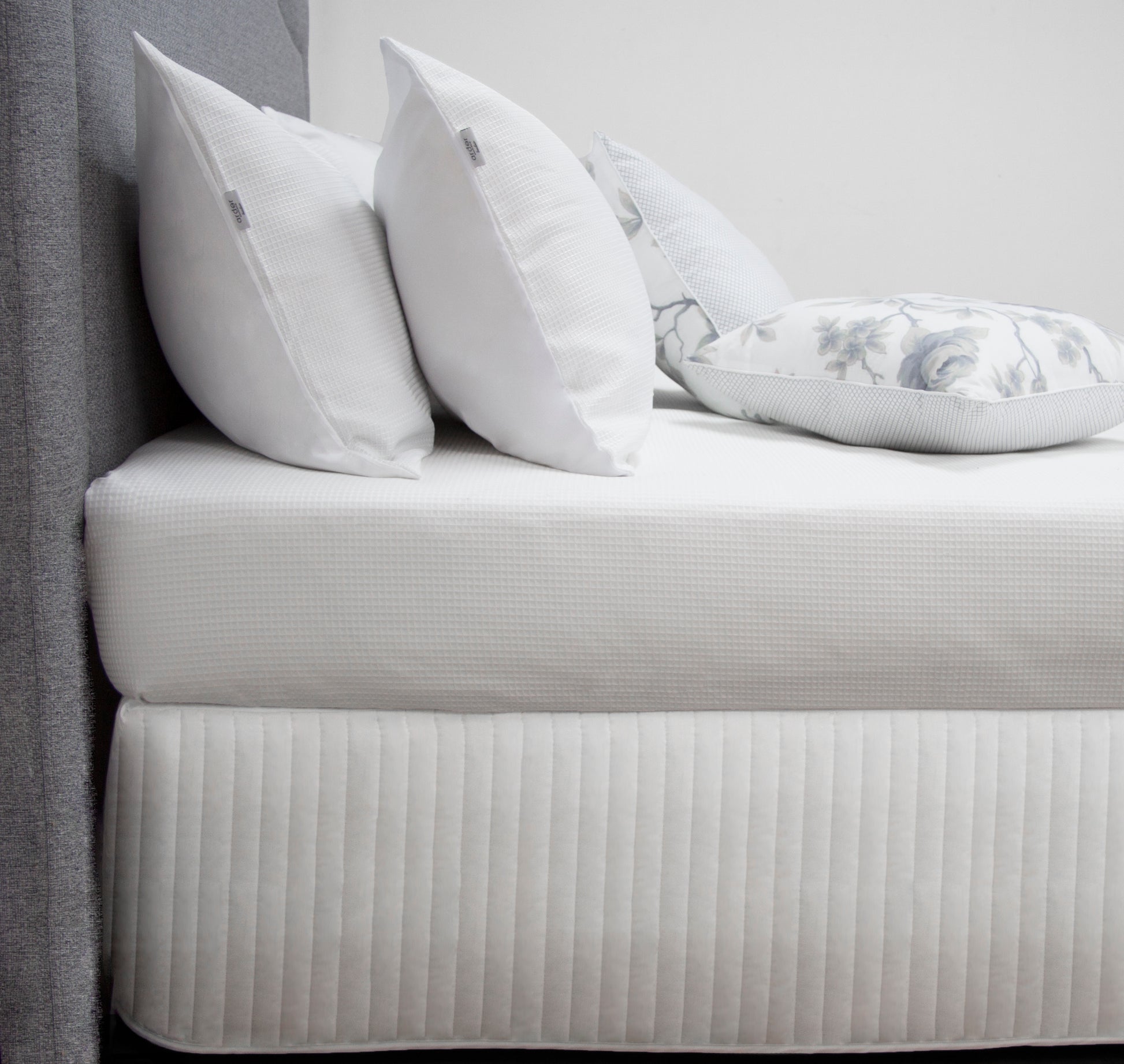 White quilted bed with decorative pillows, showcasing an elegant bed skirt valance for stylish bedroom decor.