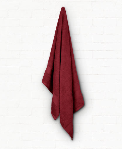 Luxurious burgundy St. Regis cotton bath towel hanging against a white background, part of a 7-piece bathroom towel set.