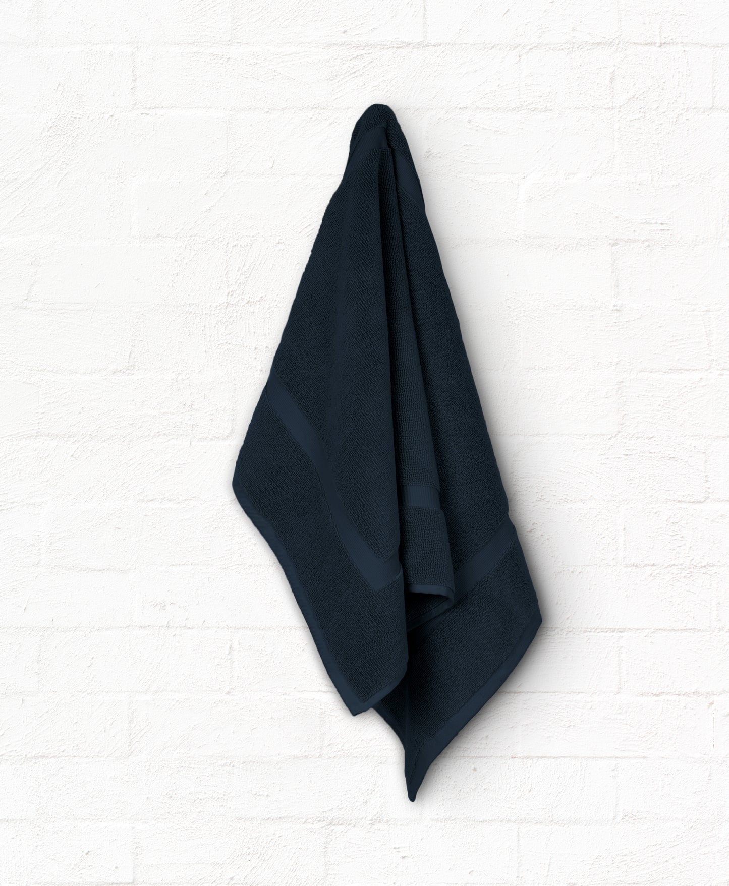 Luxury navy cotton bath towel from St. Regis 5-piece set hanging on white wall for an elegant bathroom look.