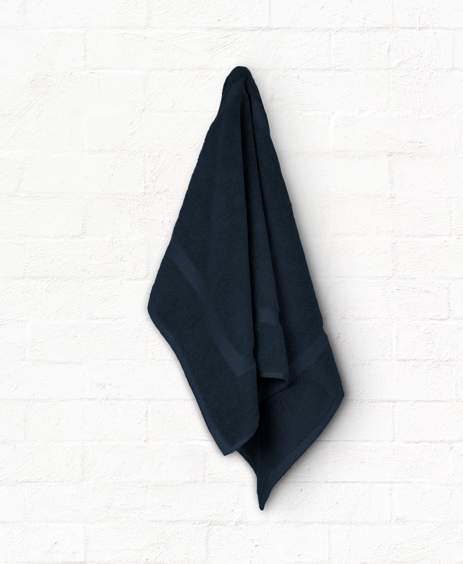 Luxury navy cotton bath towel from St. Regis 5-piece set hanging on white wall for an elegant bathroom look.