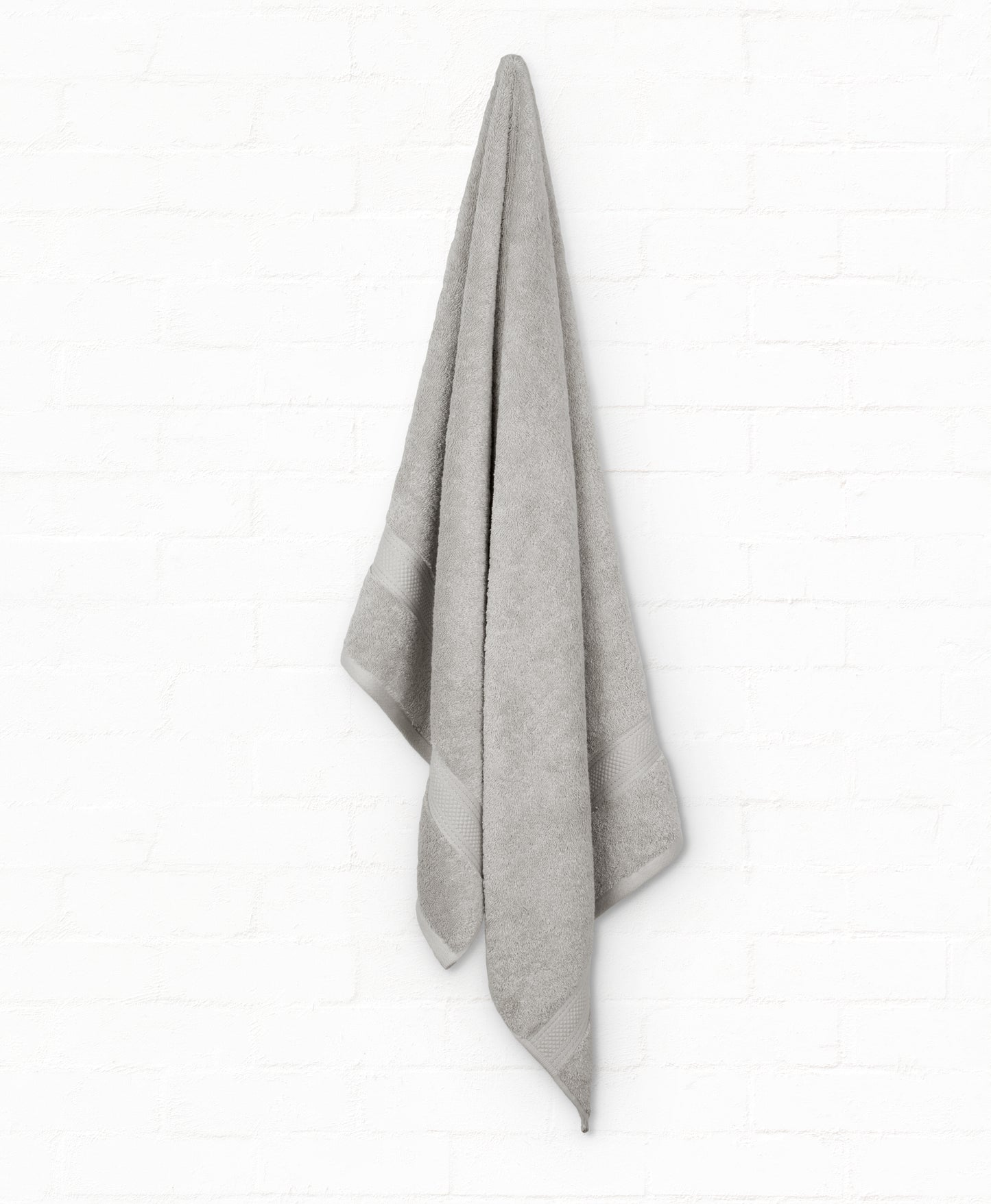 Luxury grey cotton bath towel hanging, part of St. Regis 7-piece bathroom towels set, featuring soft, absorbent 100% cotton fabric.