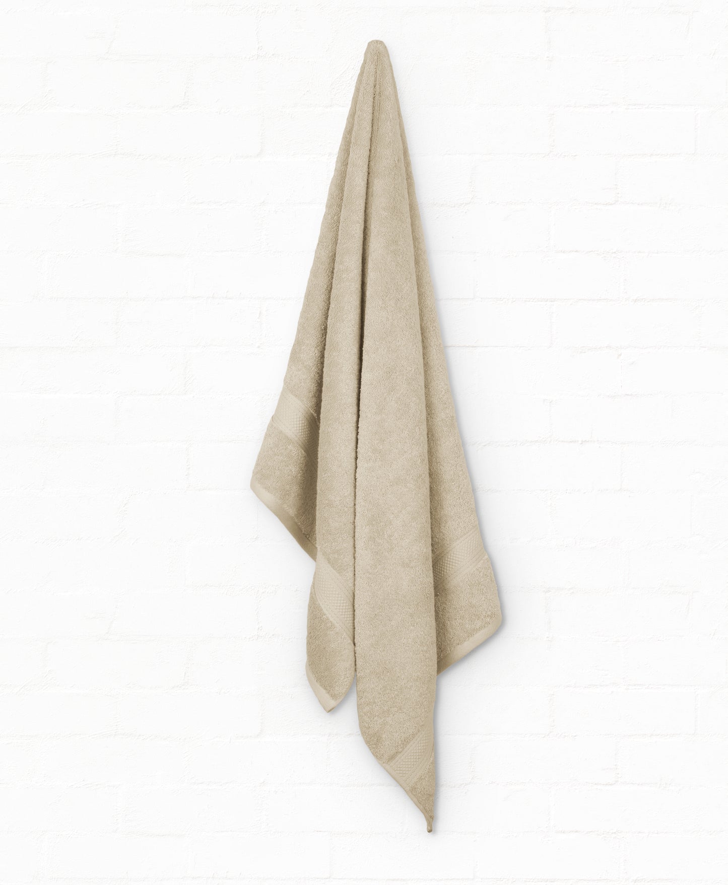 Beige St. Regis Cotton Bath Towel hanging on wall, part of 5-piece luxury bathroom towels set made from 100% cotton for ultimate comfort.