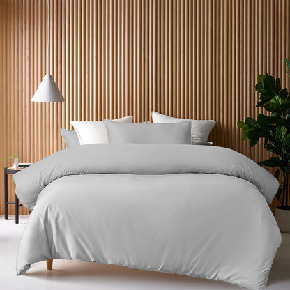 Luxurious grey bamboo cotton quilt cover set displayed on a stylish bed against a wooden accent wall.