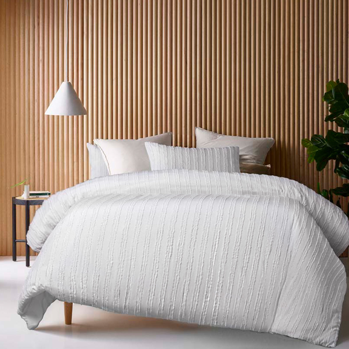 Lifestyle shot of the white quilt cover set styled in a cozy bedroom, featuring matching pillowcases and a neutral color palette for a warm ambiance.
