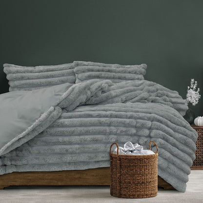 Jax Grey chunky faux fur quilt cover set displayed on a bed with matching pillowcases and a woven basket accent.