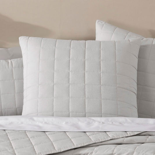 Logan and Mason Rhodes Silver square cushion with modern quilting on a bedspread, perfect for comfort and style.