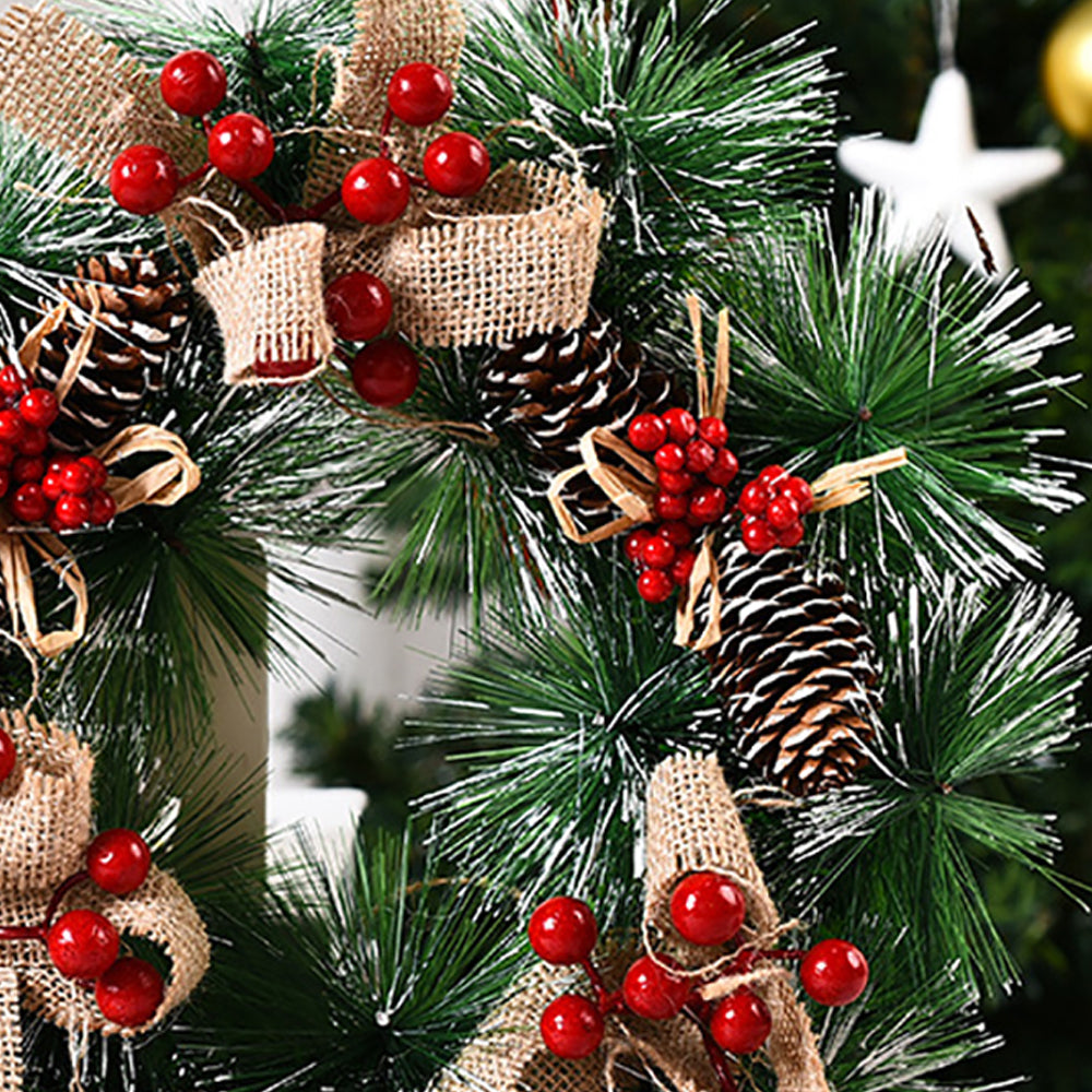 Christmas wreath with red berries, rustic bows, and pinecones, perfect for festive door decoration.