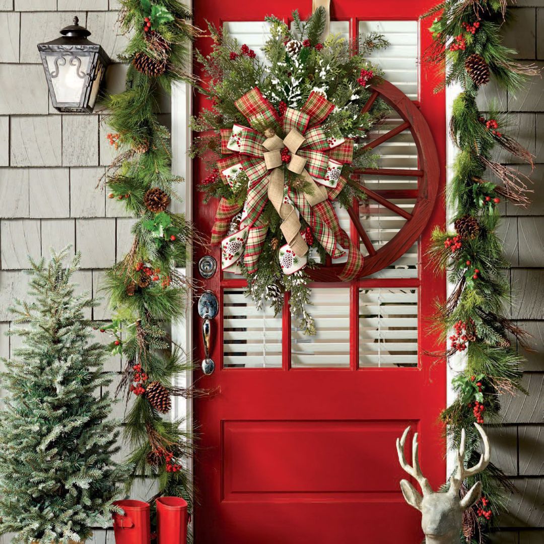 Festive Christmas wreath on a red door, adorned with greenery and a plaid bow, perfect for holiday decor.