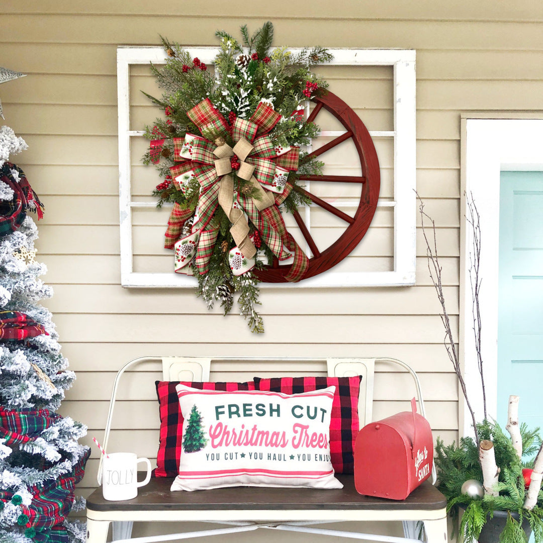 Festive Christmas red wooden wheel wreath with plaid bows on a rustic porch, complemented by holiday decor and 'Fresh Cut Christmas Trees' pillow.