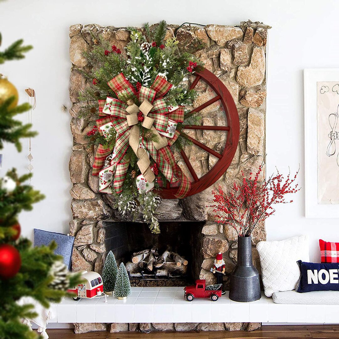 Christmas red wooden wheel wreath with plaid bow, rustic decor above stone fireplace, festive holiday atmosphere in living room.