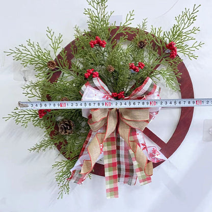 Festive Christmas wreath featuring a red wooden wheel, greenery, pine cones, red berries, and a plaid ribbon bow.