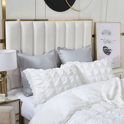 Elegant bedroom decor featuring tufted white headboard and soft gray and white pillows on a luxurious bedding set.