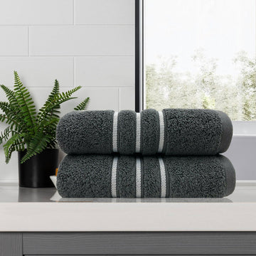 Charcoal dobby stripe bath towel set in bathroom with plant in background.