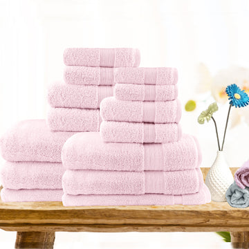 Soft baby pink cotton bath towel set displayed on a wooden table, showcasing multiple towels for a cozy bathroom aesthetic.