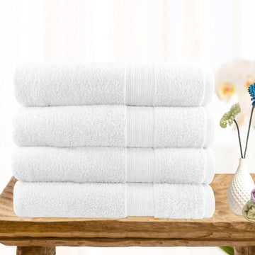 4 piece ultra-light cotton bath towel set in white stacked on wooden surface, perfect for a stylish bathroom.