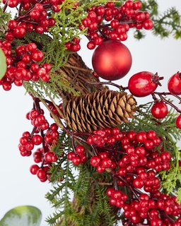 Close-up of a festive Christmas wreath with red berries, shiny ornaments, and pinecones, perfect for Aussie Xmas decorations.