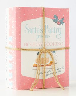 Charming pink Christmas cookbook with twine, perfect for holiday decor and festive book stack displays.