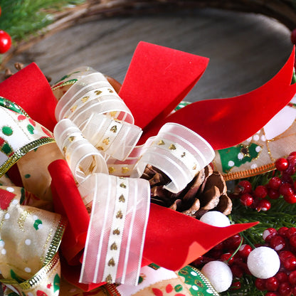 Close-up of a festive Christmas wreath featuring red ribbons, gold accents, pine cones, and vibrant red berries.