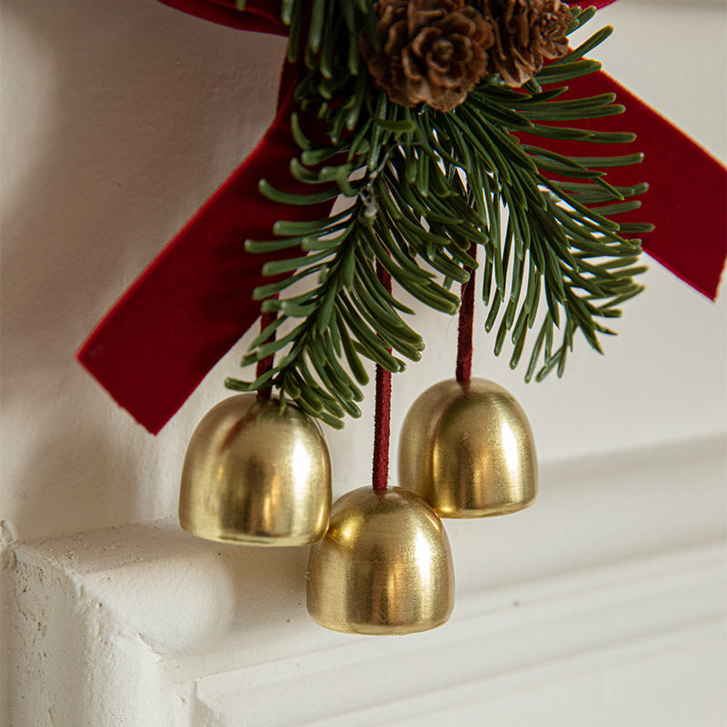 Christmas door ornament featuring golden bells, pinecones, and red ribbon for festive holiday decorations.