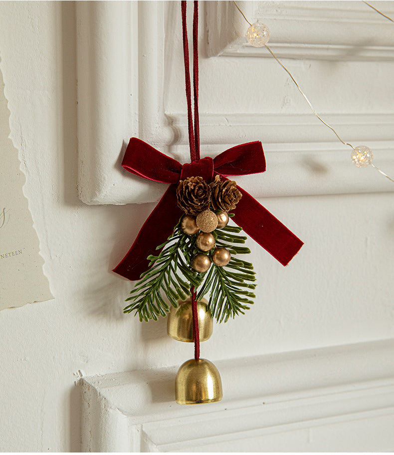 Elegant Christmas door ornament with pinecones, golden bells, and a red velvet bow, perfect for festive decor.