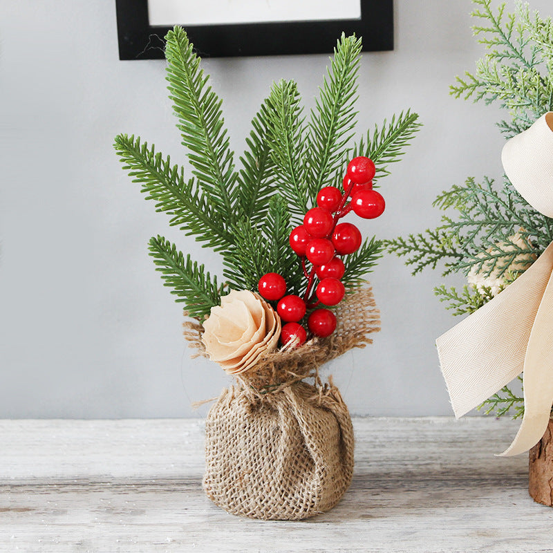 Mini Christmas pine tree with red berries in burlap base, perfect for festive table decorations.