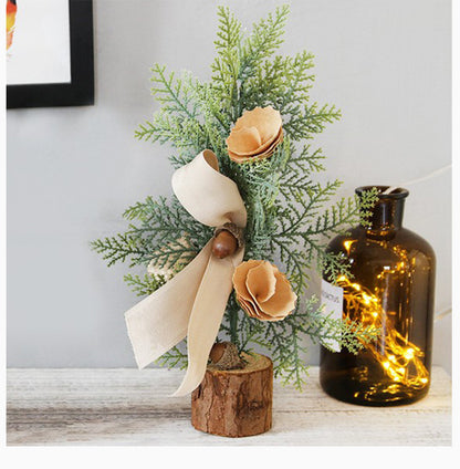 Rustic mini tabletop tree with burlap bow and acorn accents for Christmas table decorations.