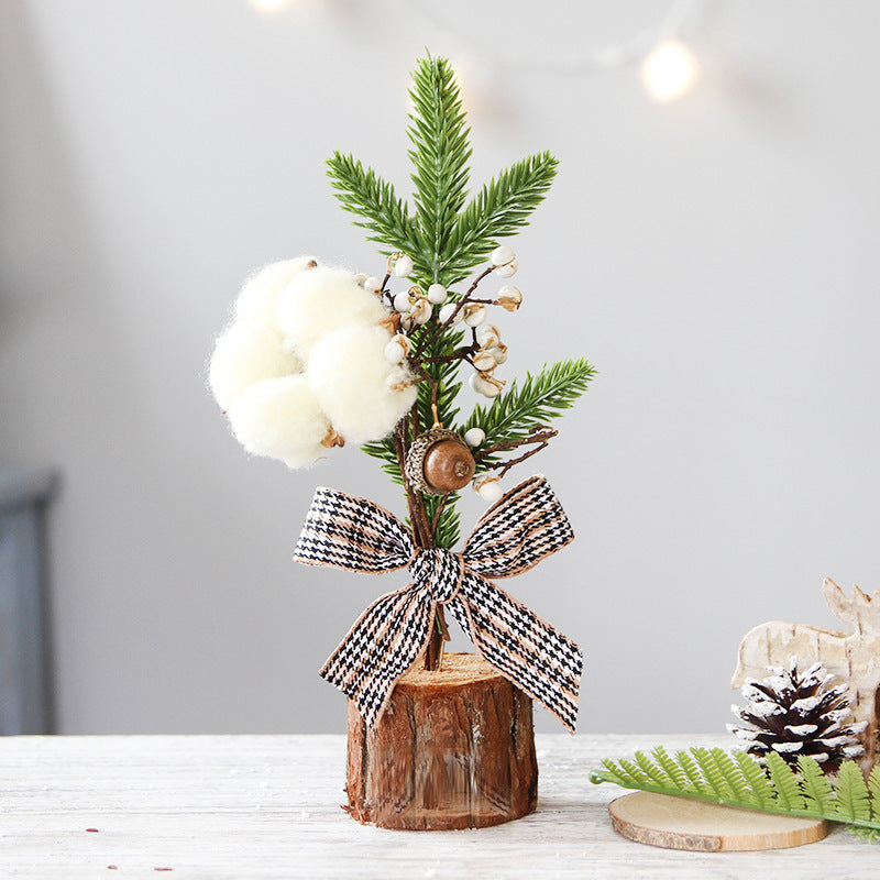 Mini rustic Christmas tree with cotton and plaid bow, perfect for festive table decorations this holiday season.