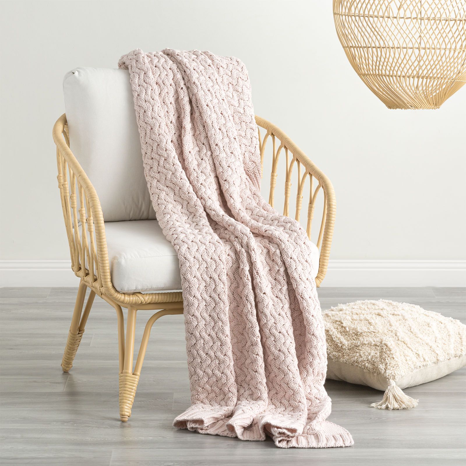 Primrose pink chunky knit throw blanket on chair, thick knitted texture, stylish rib knit edge, ideal for cozy home decor.